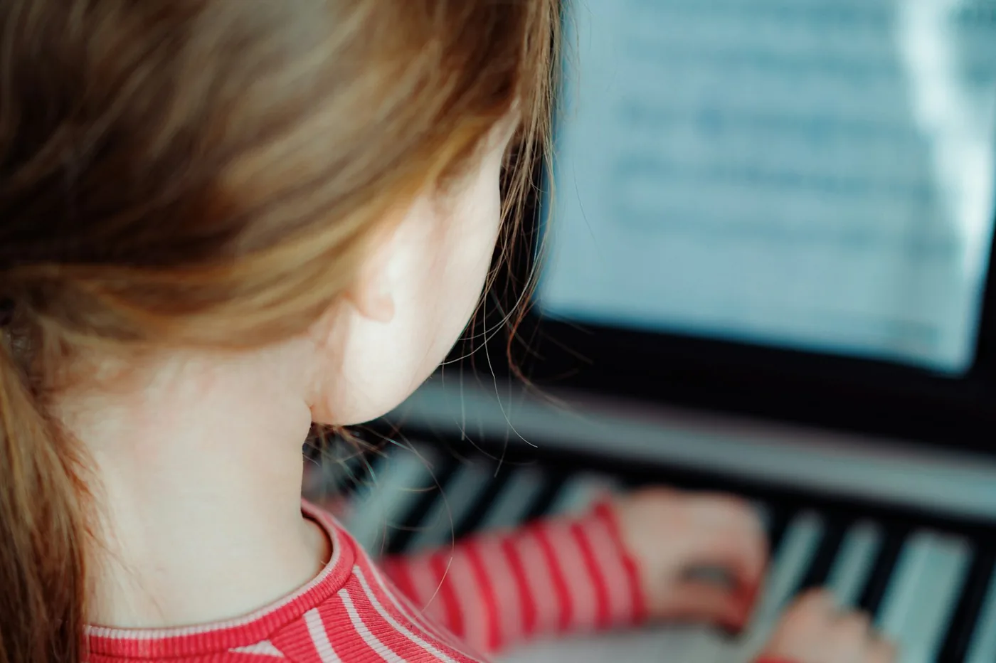 Child focused on playing keyboard with sheet music during music therapy. Music therapy for ADHD and attention challenges in Thornhill, Vaughan at Young Sprouts Therapy.