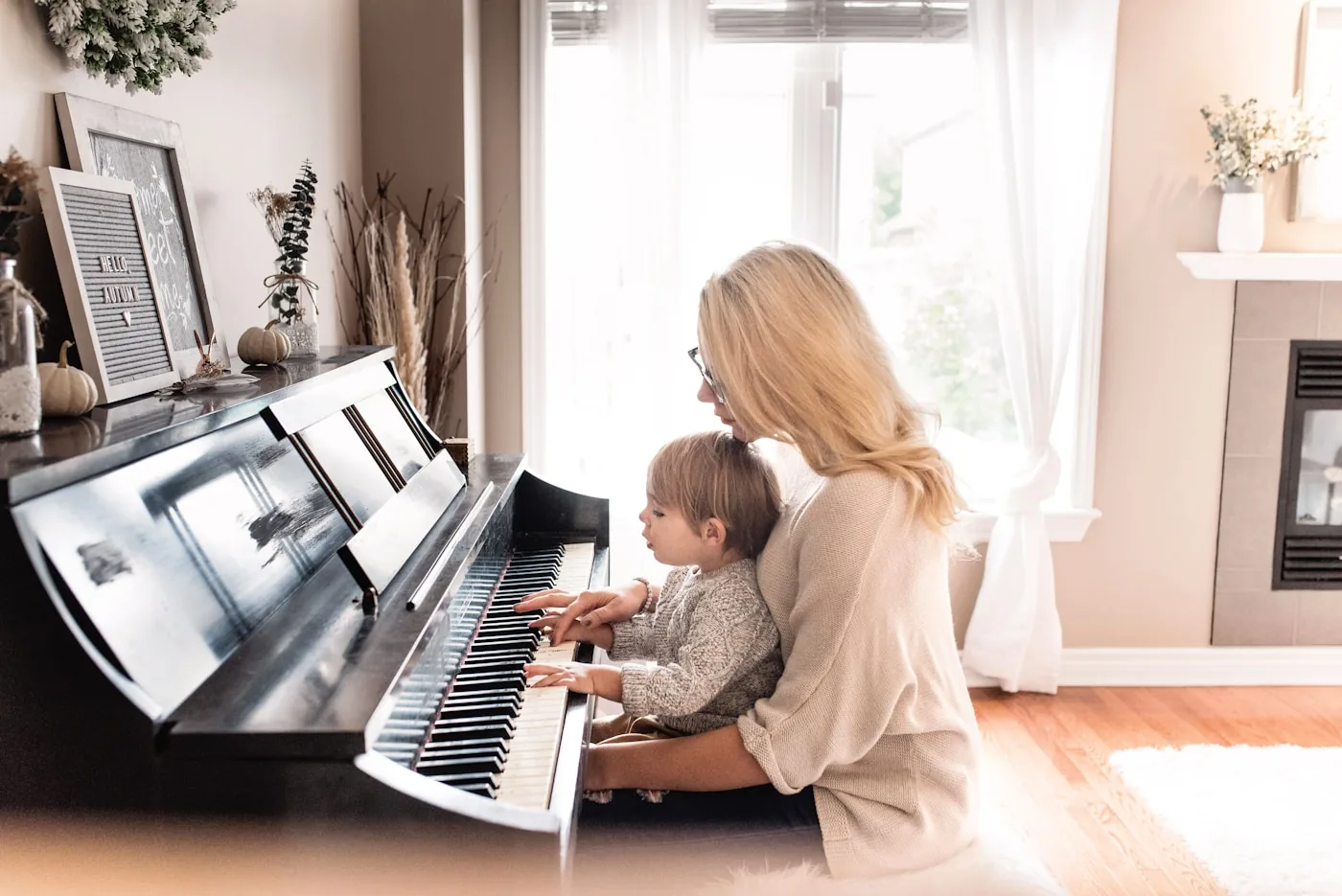 Adult gently guiding a young child at the piano in a calm home setting. Music therapy for anxiety in Thornhill, Vaughan at Young Sprouts Therapy.