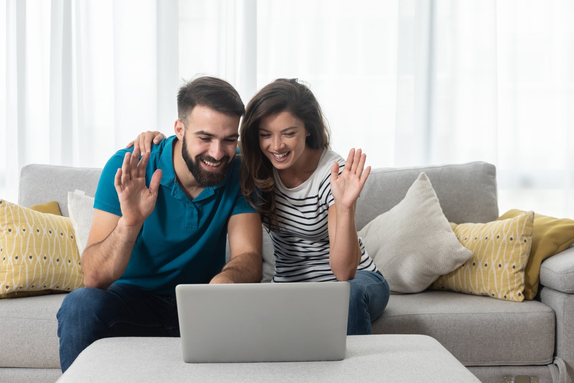 Couple sitting together on a couch, having an online couples counselling session.