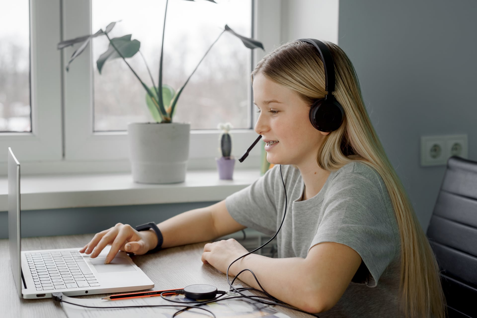 Teenager wearing headphones and talking to a therapist during a virtual counselling session.