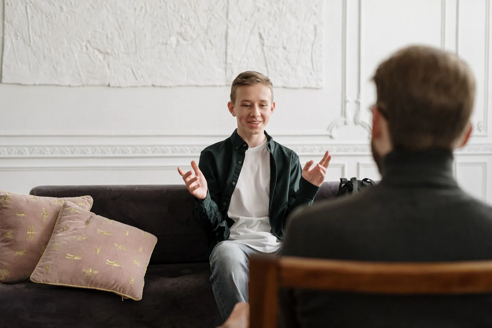Teenage boy smiling and talking with a male therapist during a session