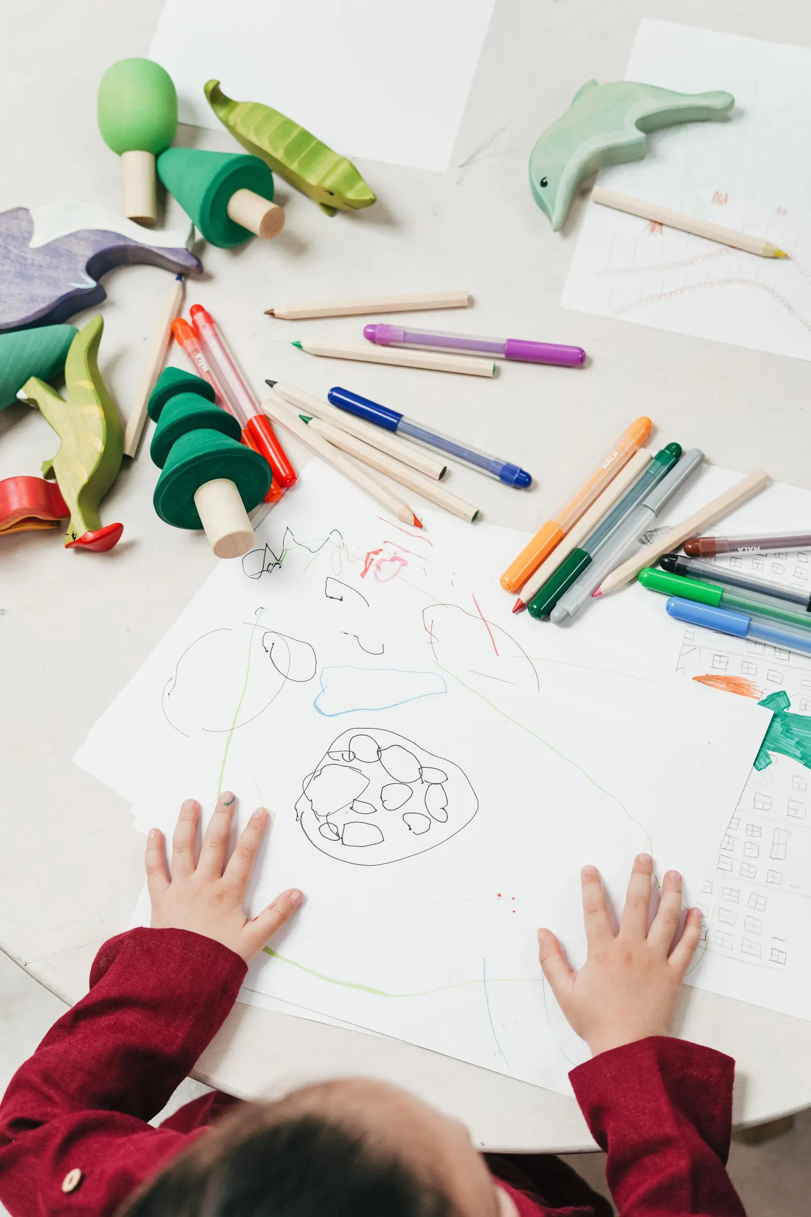 Child drawing with dark crayons at a kitchen table, a common moment that leaves parents wondering what it means
