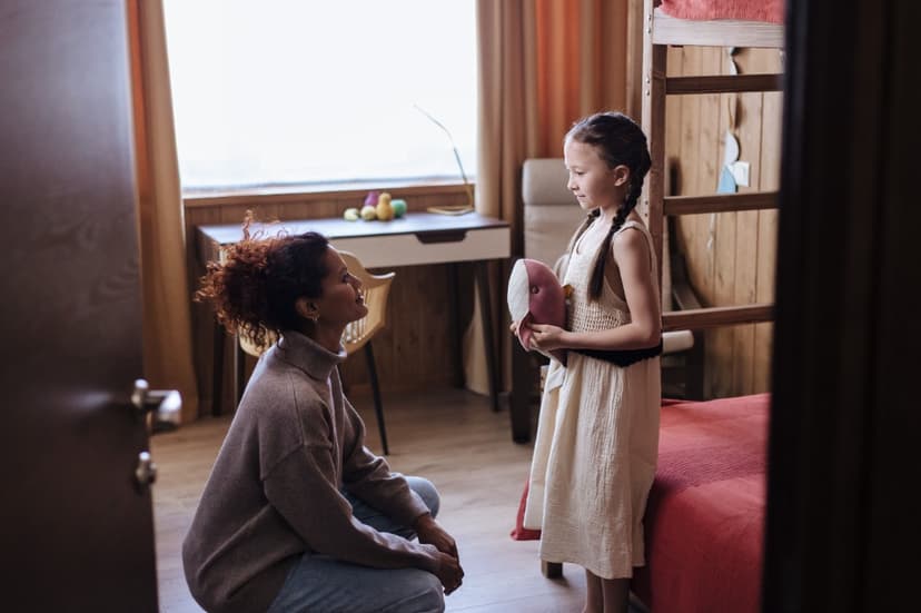 Mother crouches to eye level to speak gently with her young daughter holding a stuffed animal, illustrating supportive parenting for a highly sensitive child Mother crouches to eye level to speak gently with her young daughter holding a stuffed animal, illustrating supportive parenting for a highly sensitive child