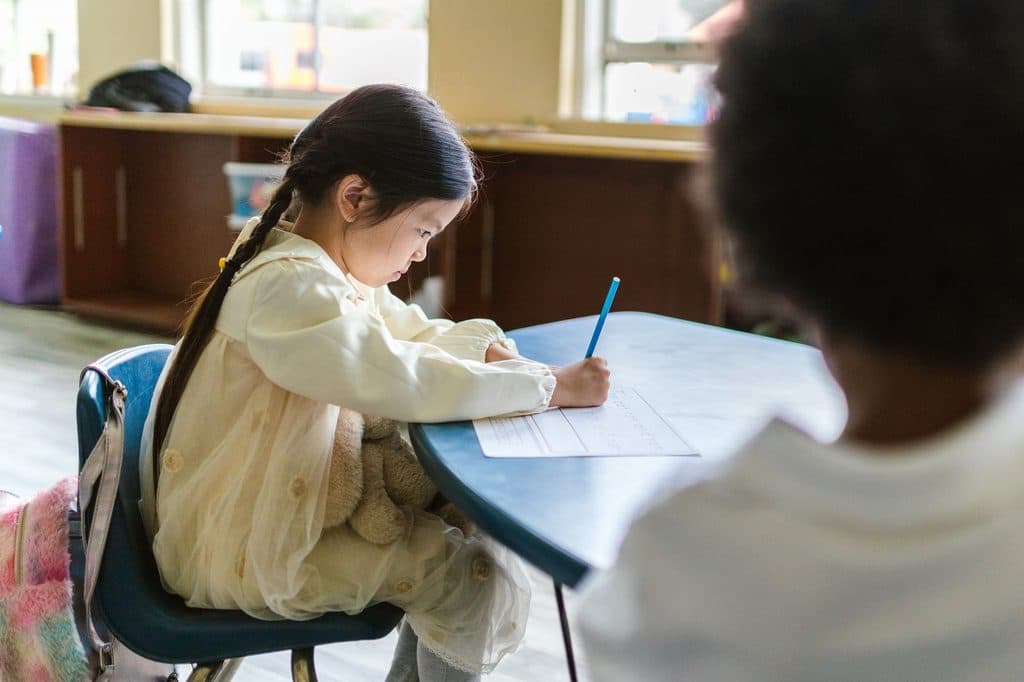 Elementary-aged child gripping a pencil tightly while writing at a desk, illustrating handwriting difficulty and possible dysgraphia