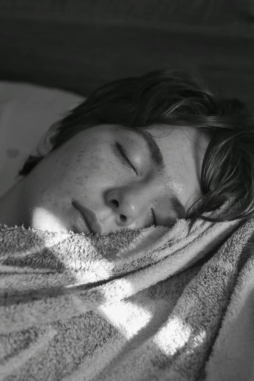Teenager sleeping late under a heavy blanket on a dark winter morning, a common sign of seasonal depression Teenager sleeping late under a heavy blanket on a dark winter morning, a common sign of seasonal depression