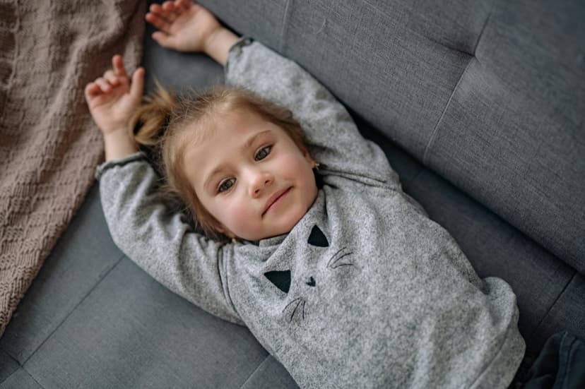 Young child lying quietly on a couch with a withdrawn, subdued expression Young child lying quietly on a couch with a withdrawn, subdued expression
