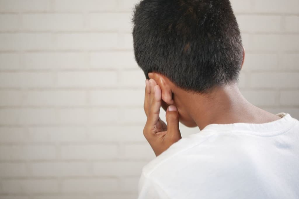 Young boy seen from behind covering his ear with one hand, illustrating sound sensitivity and sensory processing challenges in autism