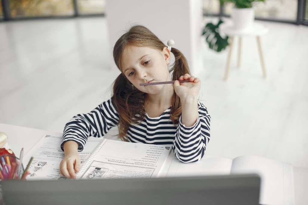 Young girl daydreaming at her desk — a common but missed sign of ADHD in girls