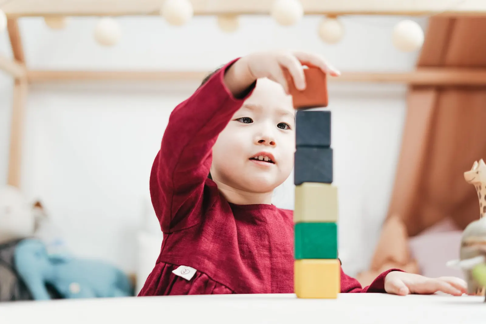 Young child stacking wooden blocks on the floor