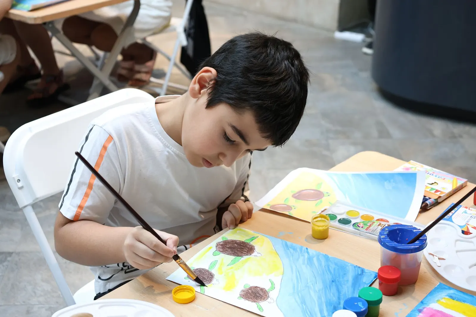 Child painting at a table with bright colours