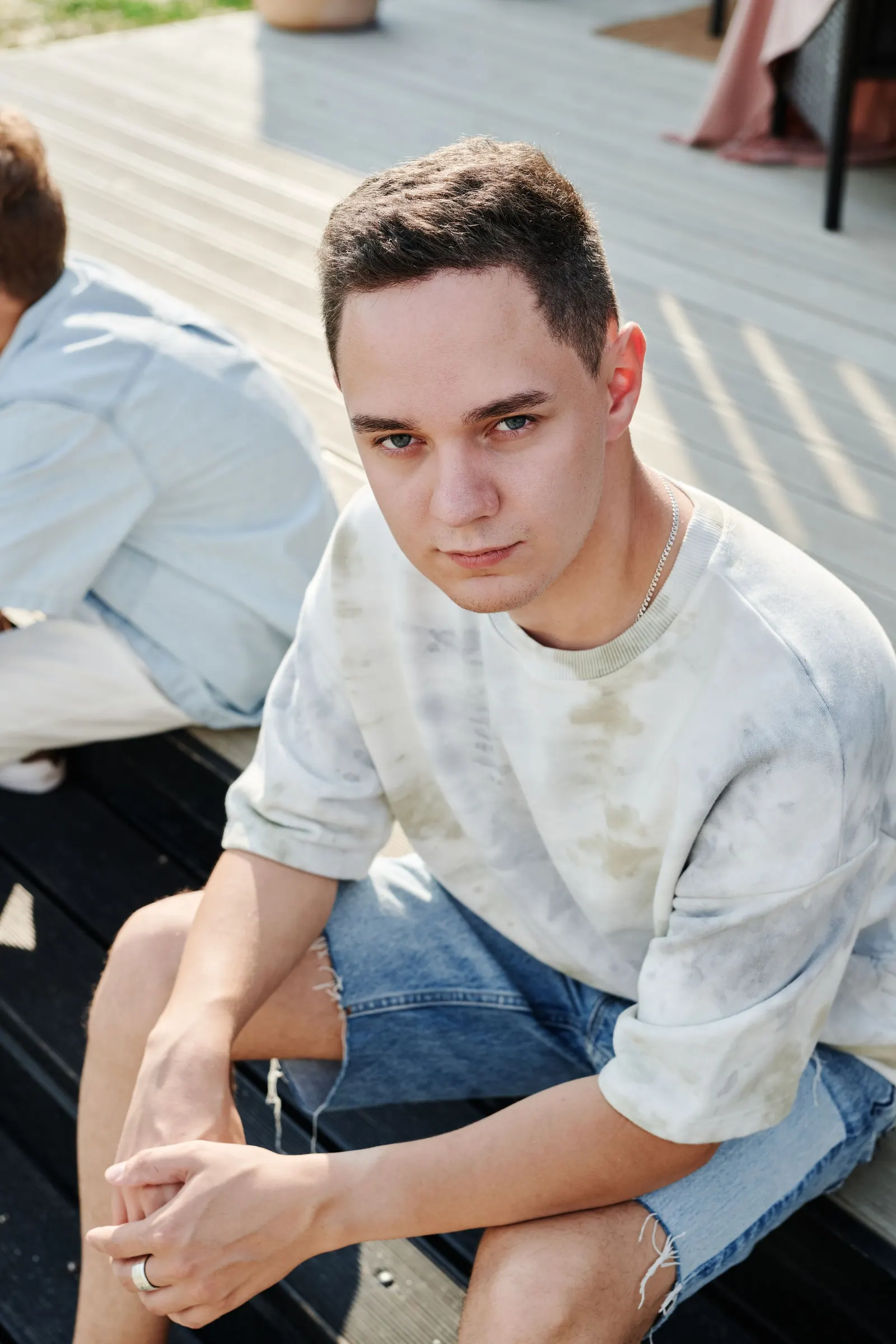 Teenage boy sitting outdoors looking toward the camera