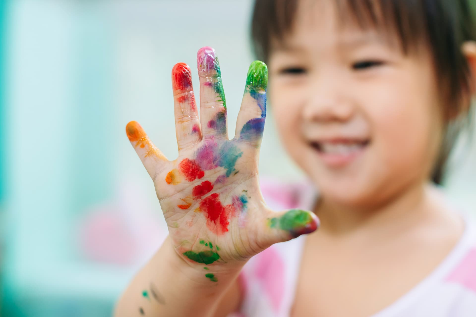 Child engaging in sensory play with colorful hand painting during occupational therapy in Thornhill