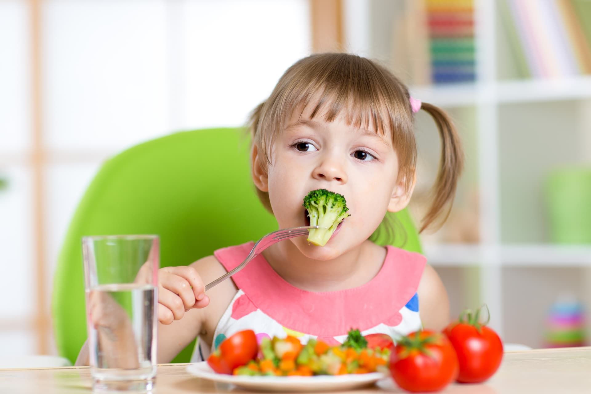 Child eating healthy foods by themselves demonstrating feeding skills