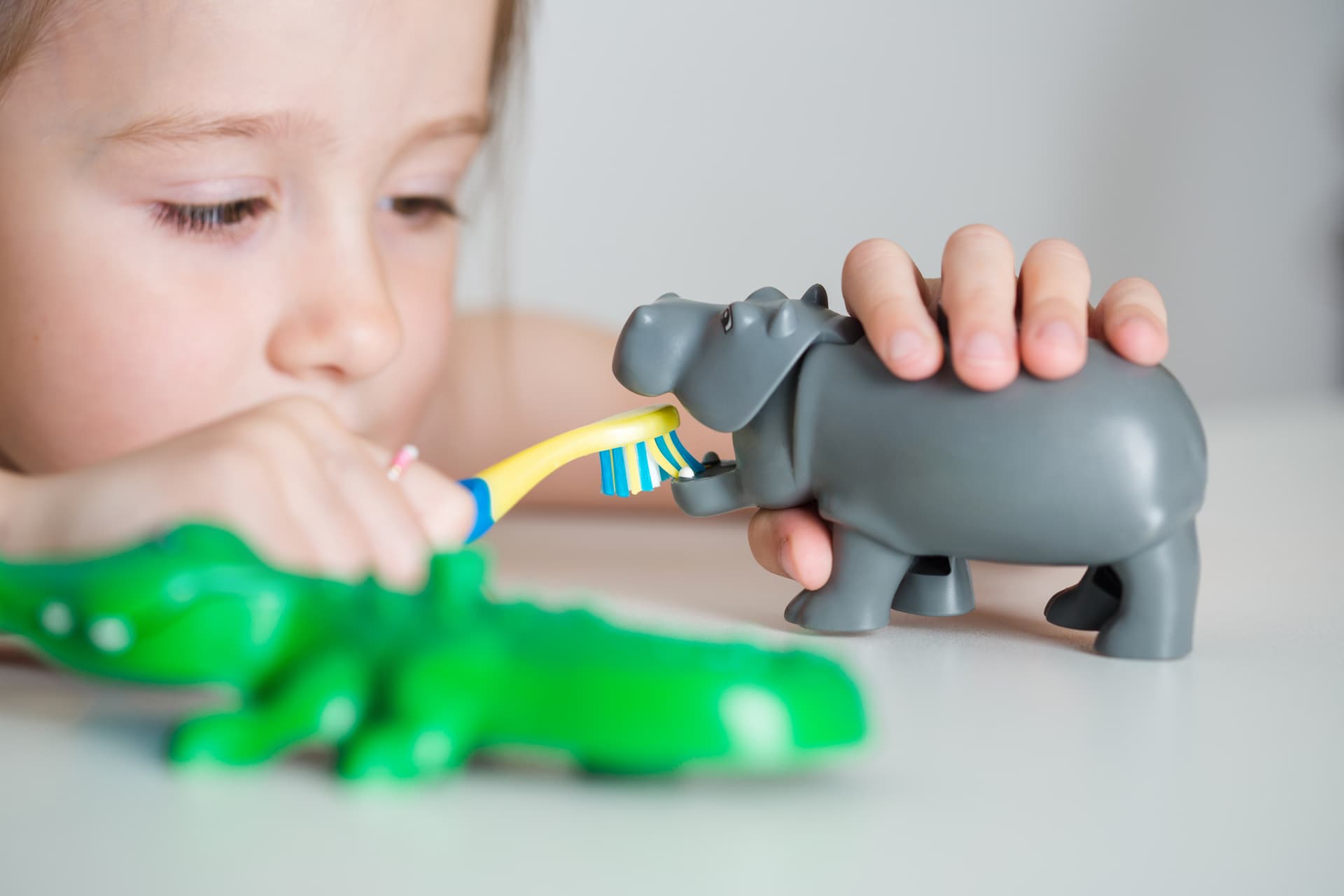 Child learning self care by brushing toy's teeth