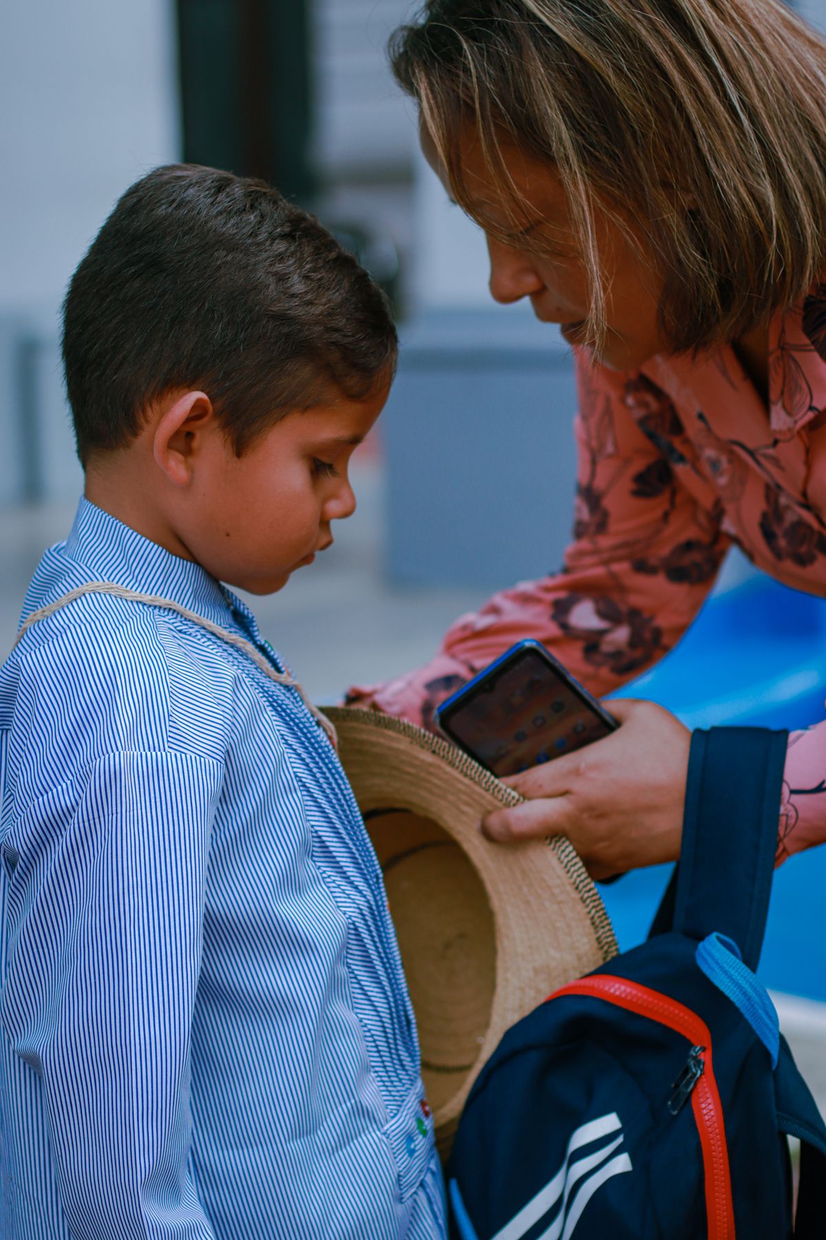 Parent kneeling to help a young child with their backpack before a school day, illustrating the separation anxiety common in JK and SK drop-offs
