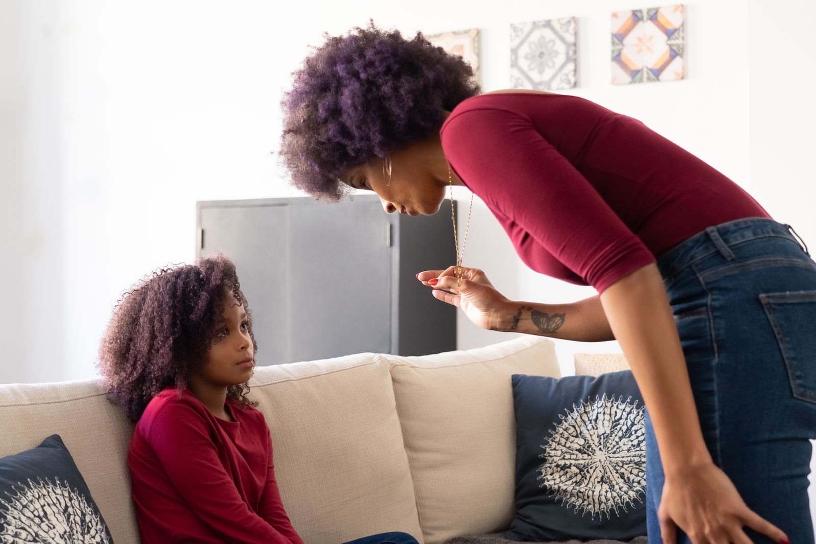 Parent leaning down to talk calmly at eye level with a seated child, illustrating how to talk through back-to-school worries