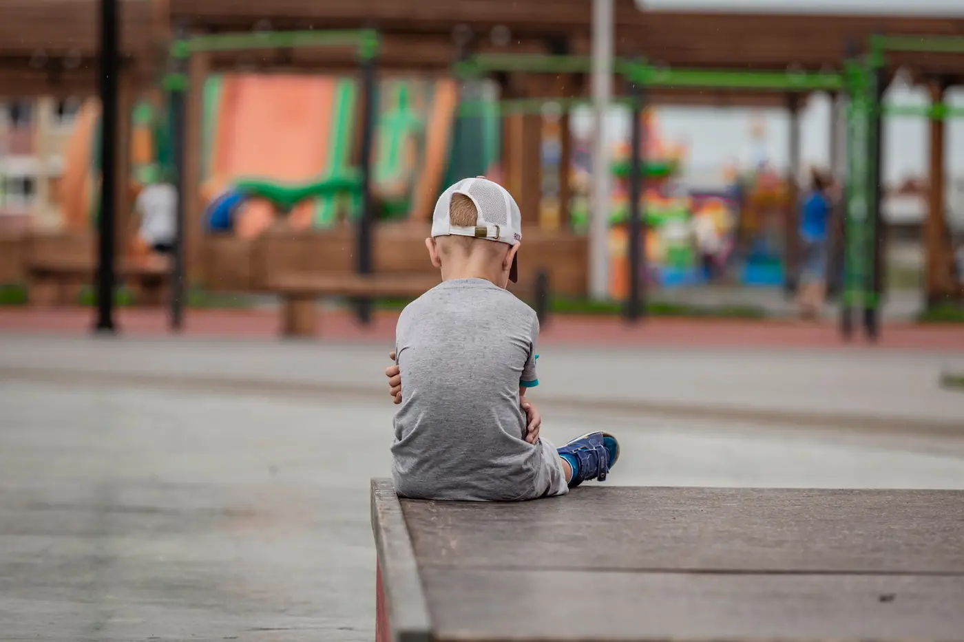 Child sitting alone at recess, a common sign of social bullying or exclusion