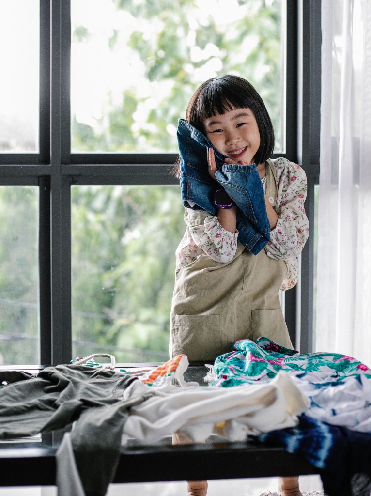 Young girl smiling while holding soft denim fabric to her cheek, illustrating how a highly sensitive child can be deeply attuned to everyday textures